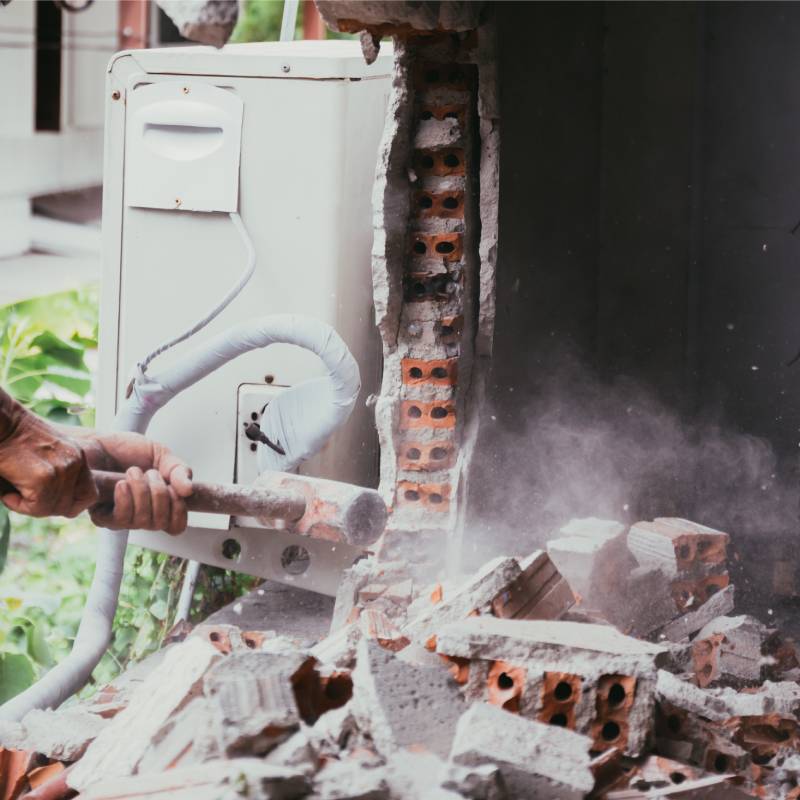 Unrecognizable builder using a sledgehammer breaking and smashing the wall fallen into debris - breaking wall and challenges concept Demolition Company Central Coast, House Demolition Central Coast, Residential Demolition Central Coast, Commercial Demolition Central Coast, Asbestos Removal Central Coast, Site Clearing Central Coast, Internal Strip-Out Central Coast, Demolition Services NSW