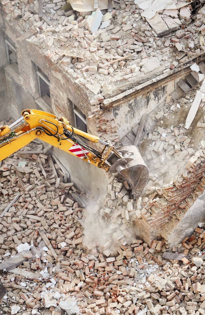 Old brick building demolition with an excavator bucket in dust cloud, view from above. House, Residential & Commercial Demolition Company Bondi Junction & Beach | ABC Demo Group